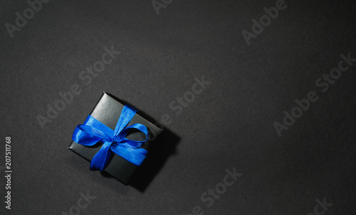 black box tied with blue ribbon on a black background