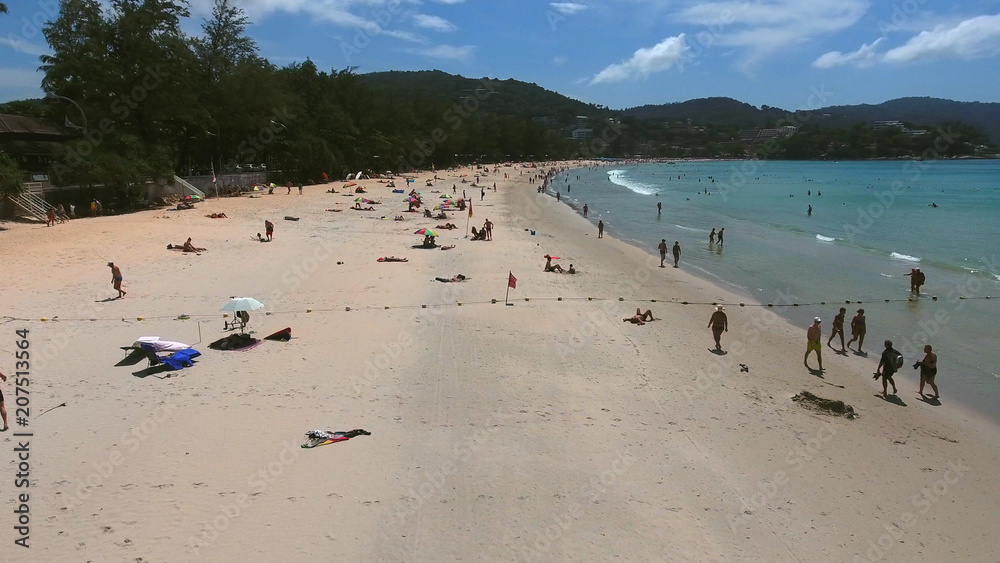 Fototapeta premium PHUKET, THAILAND - 20 JAN 2017: Aerial view of crowd of tourists get rest on sea beach near little village at summer sunny day