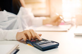 Closeup woman calculate finance data with calculator on office table with morning light.
