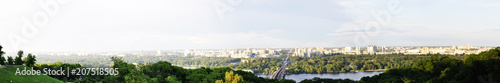 Panorama of the big city. Landscape of the green park with trees, large bridge over the river and the urban buildings.