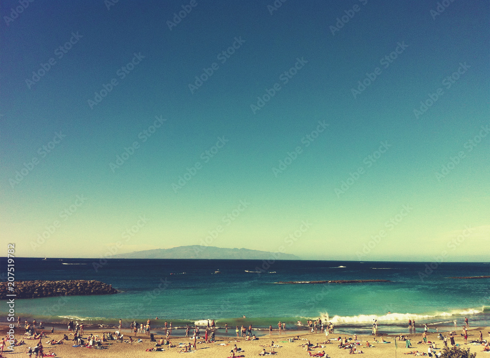 Toned photo of the beach and the zone in the style of the 80's. People on the beach. Beautiful sea and mountain views