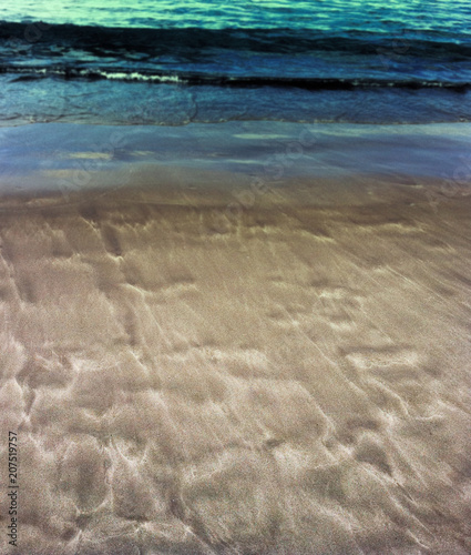 Beautiful patterns from the waves on the sand. Volcanic sand on the beach. Summer