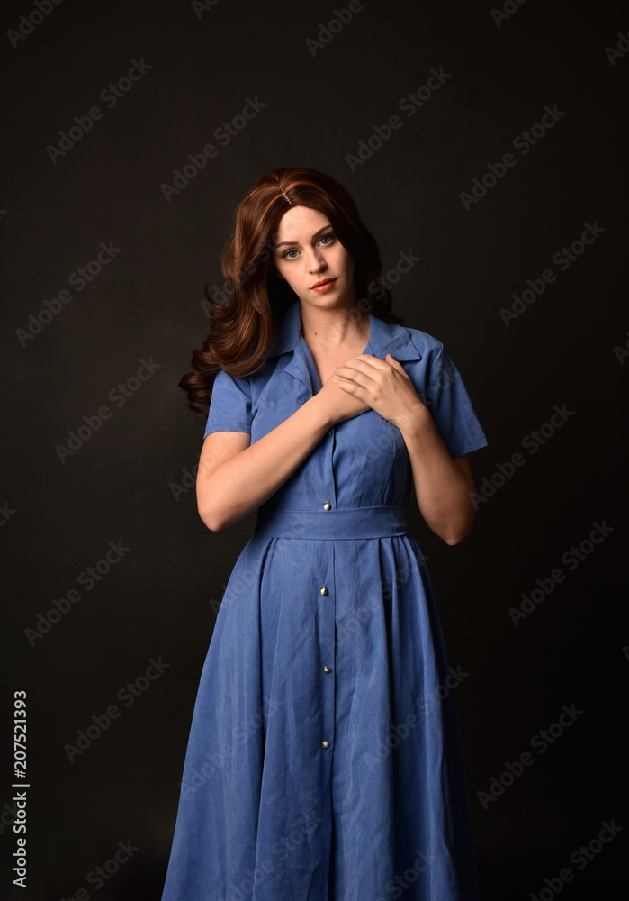 3/4 portrait of brunette lady wearing blue dress. posed on black studio background. 3/4 portrait of brunette lady wearing blue dress. posed on black studio background.