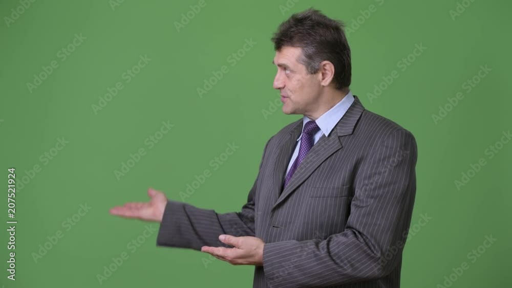 Mature handsome businessman against green background