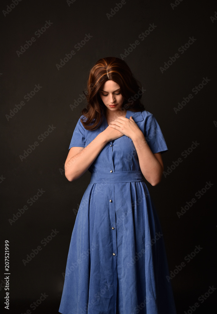 3/4 portrait of brunette lady wearing blue dress. posed on black studio background. 3/4 portrait of brunette lady wearing blue dress. posed on black studio background.