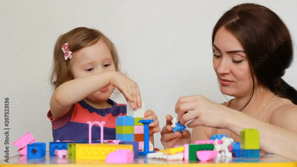 Mother and girl child busy building a constructor. Mother and girl child busy building a constructor.