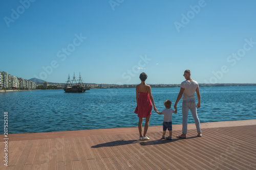 happy family of father, mother and child son having fun in nature looking on bay.