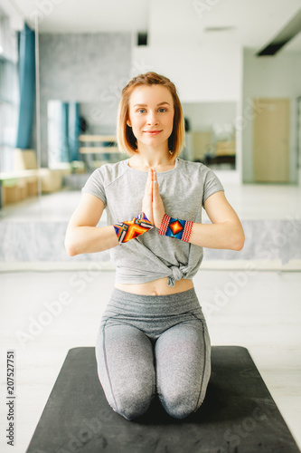 Calm and satisfied female yoga instructor finishing her class with clasped palms in Namaste, thanking the Teacher, pupils for this lesson and experience. photo