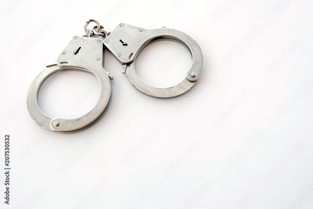 Handcuffs on a white background in the upper left corner of the frame. Copy space. The concept of violation of the law in the financial sphere, fraud, corruption, bribery. Handcuffs on a white background in the upper left corner of the frame. Copy space. The concept of violation of the law in the financial sphere, fraud, corruption, bribery.