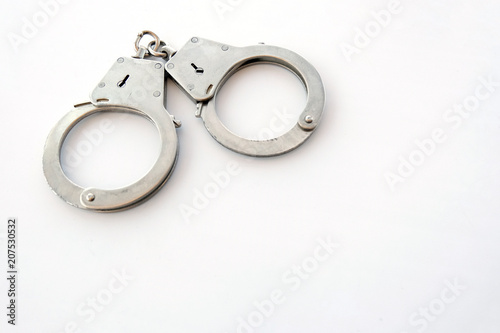 Handcuffs on a white background in the upper left corner of the frame. Copy space. The concept of violation of the law in the financial sphere, fraud, corruption, bribery.