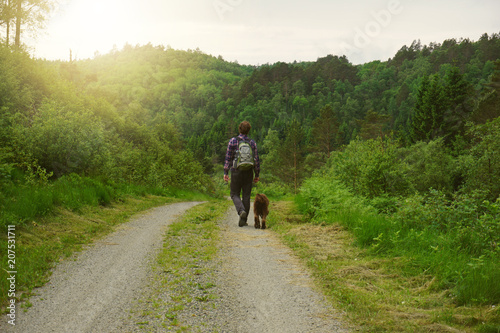 Mann geht mit Hund auf einem Weg während Sonnenuntergang © Fabian