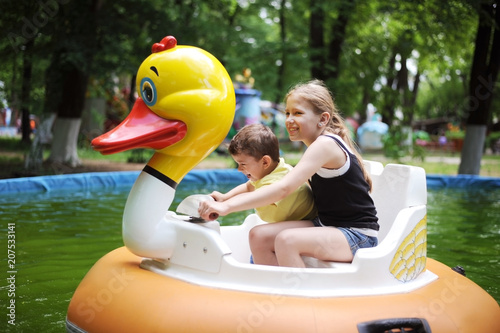 Fotografie Diverse children - a little boy and a teenage girl riding on a water attraction