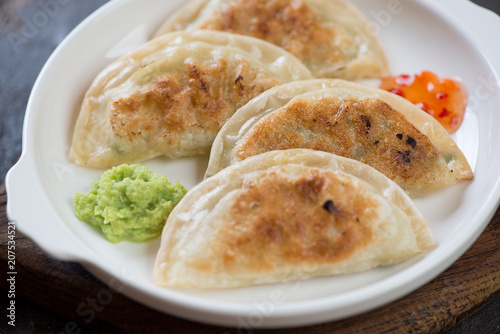 Closeup of pan fried korean potstickers served on a white plate, selective focus