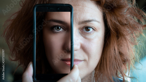 Woman Holding a smartphone covering half of her face, showing the transformation of Before and After retouching, Concept of Social Media affects out life
