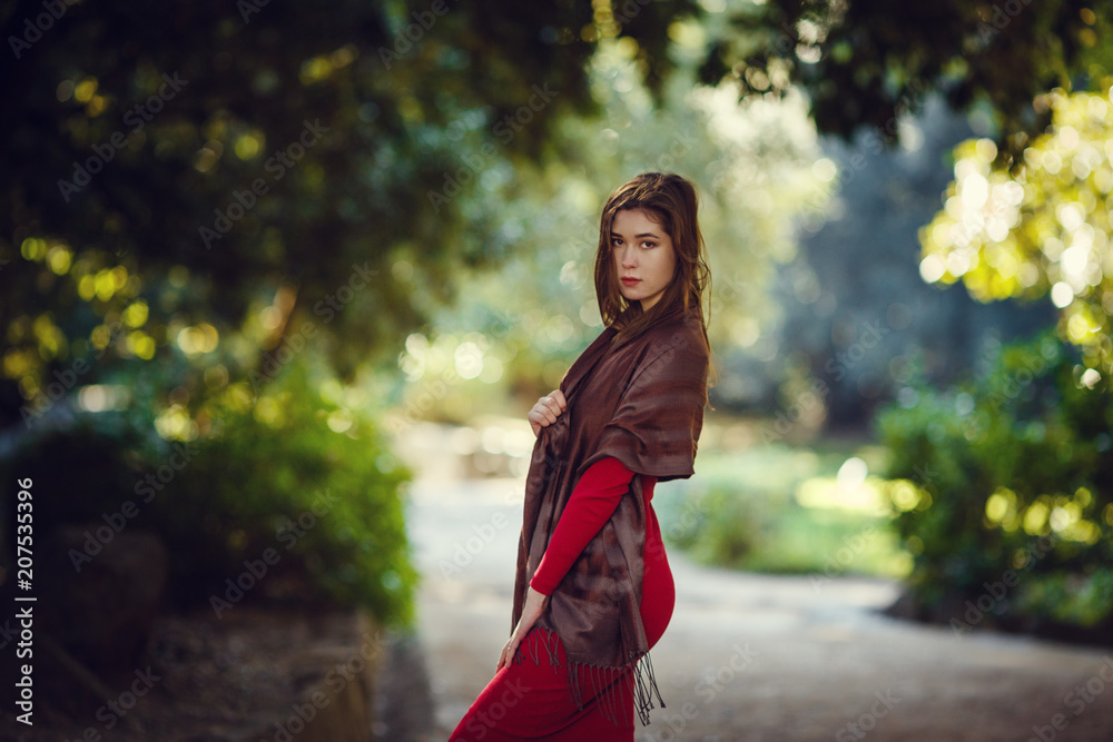 Beautiful girl in a red dress walks along the spring park Beautiful girl in a red dress walks along the spring park