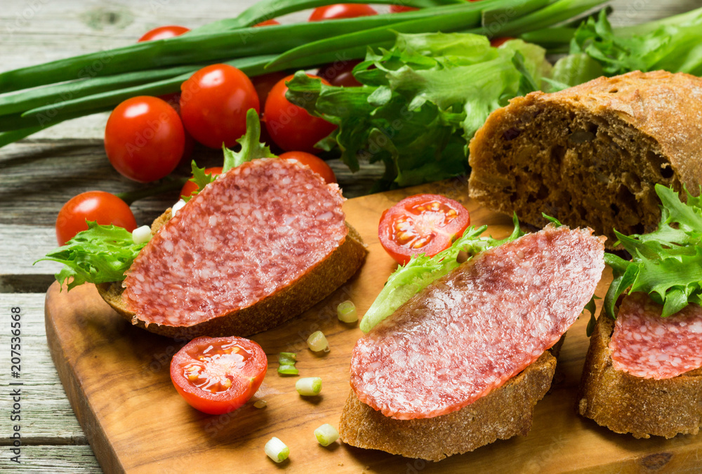 Sandwiches with sausage, tomatoes, onions on a cutting board. Sandwiches with sausage, tomatoes, onions on a cutting board.