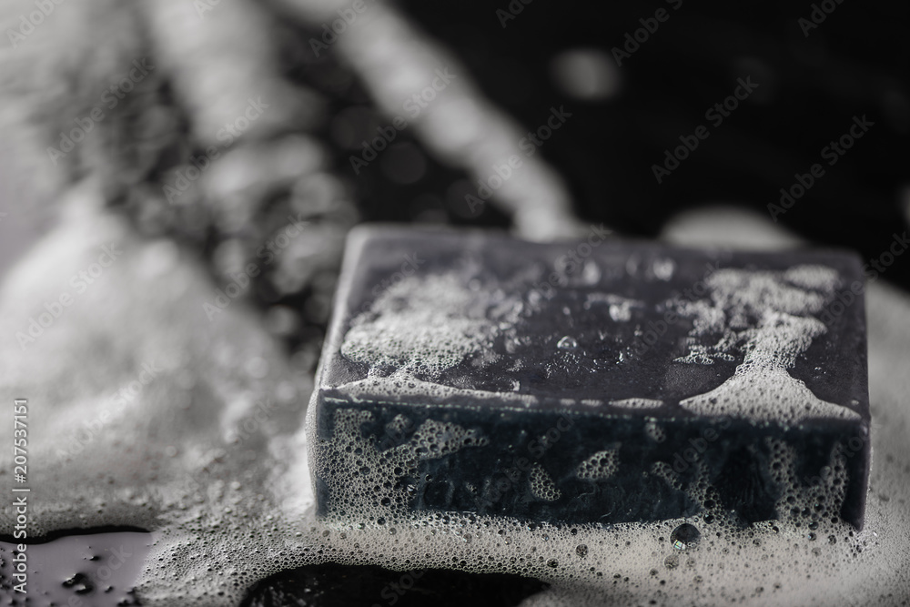 block of natural carbon charcoal soap on black stone background with bubbles block of natural carbon charcoal soap on black stone background with bubbles