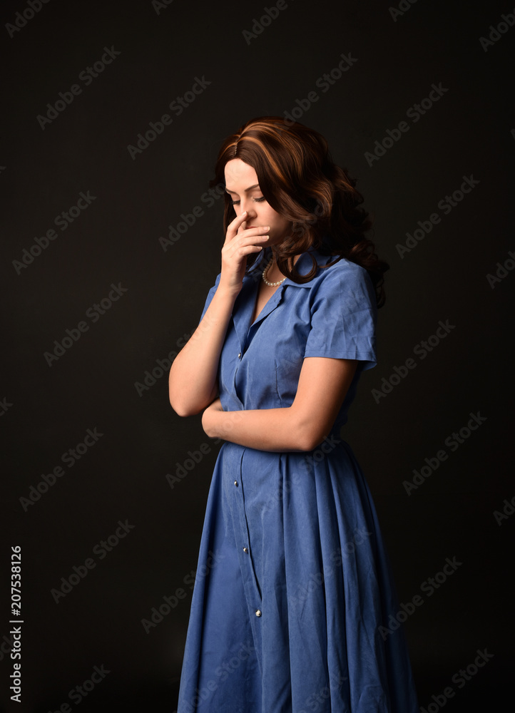 3/4 portrait of brunette lady wearing blue dress. posed on black studio background. 3/4 portrait of brunette lady wearing blue dress. posed on black studio background.