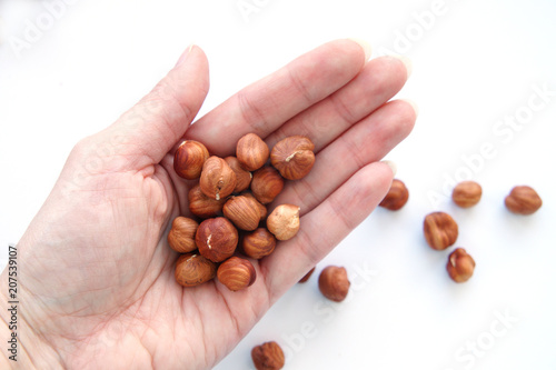 handful of peeled hazelnuts in a female hand on a white background