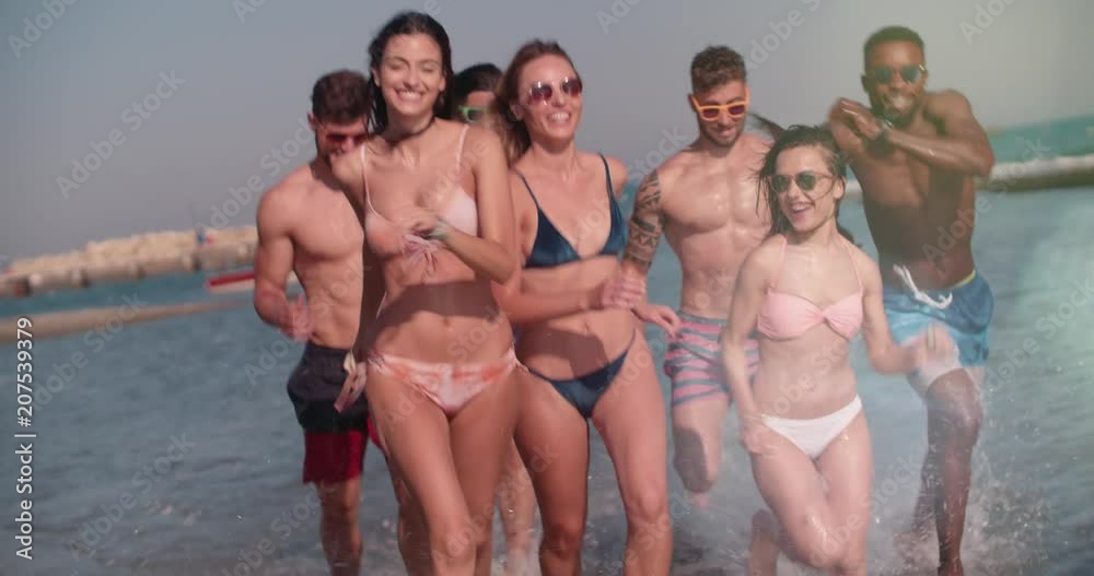 Young multi-ethnic friends on summer holidays running on the beach