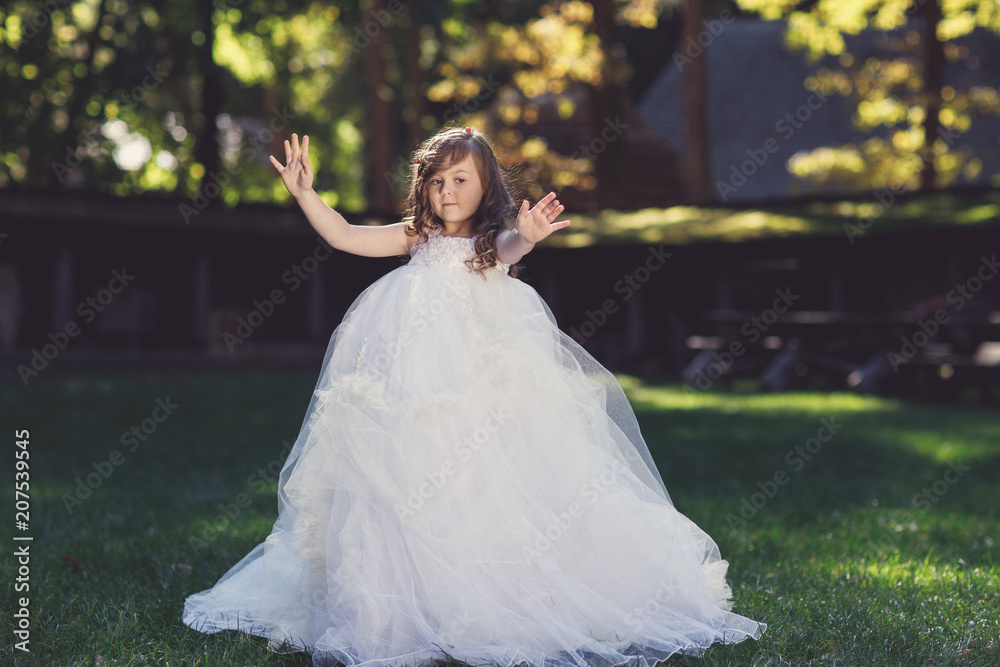 Outdoor portrait of adorable smiling little girl in white dress