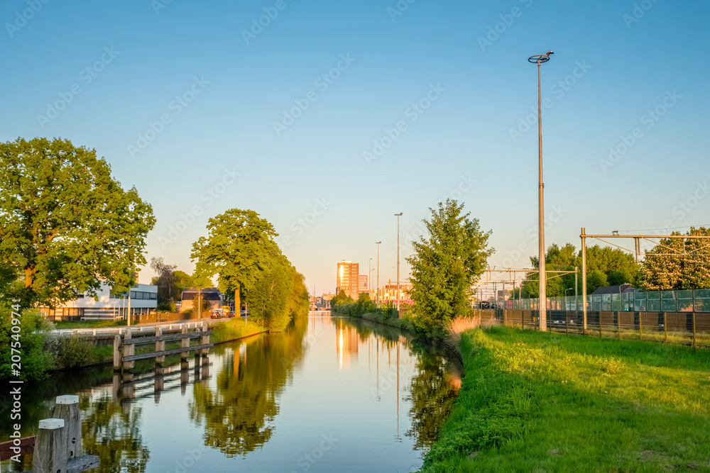 Fototapeta premium On a hot May evening we are standing on the Island Bridge ('Eilandbrug') looking over the channel towards the Central Train Station of the Dutch city of Almelo.