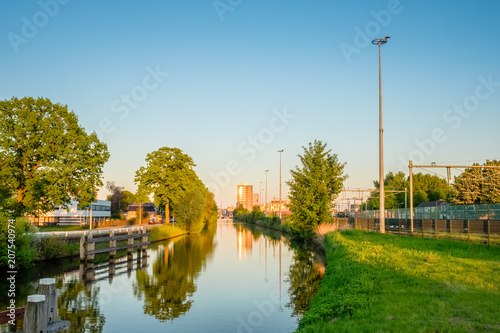 Fototapeta Naklejka Na Ścianę i Meble -  On a hot May evening we are standing on the Island Bridge ('Eilandbrug') looking over the channel towards the Central Train Station of the Dutch city of Almelo.