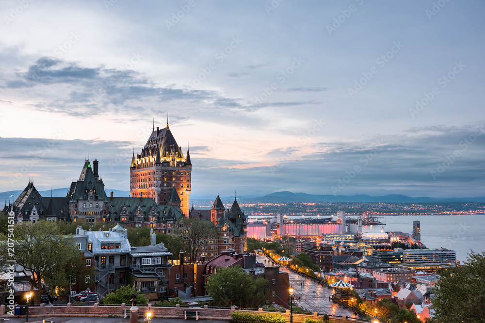 Fototapeta premium Pejzaż miejski lub panoramę miasta Quebec, Kanada, Chateau Frontenac, park i ulice starego miasta podczas zachodu słońca z oświetlonym zamkiem, czerwony budynek Espace 400e