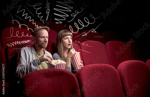 Young cute couple sitting in cinema, and eating popcorn while watching movie with doodle graphics © ra2 studio