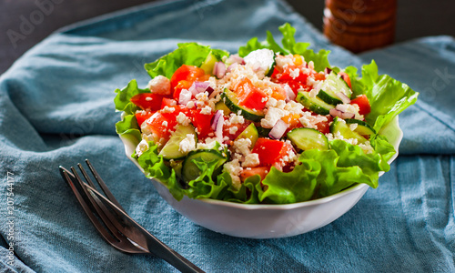 vitamin salad with tomato, cucumber, onion, lettucce and cottage cheese in white bowl on table photo