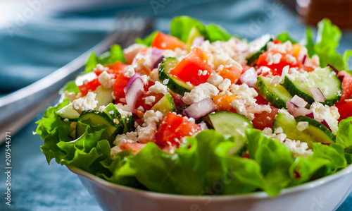 vitamin salad with tomato, cucumber, onion, lettucce and cottage cheese in white bowl on table photo