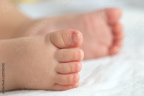 Little baby feet on white soft cloths in the background. © Teerachai