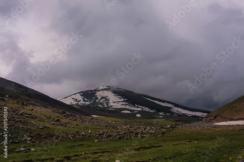 Fotografija green rocky valley and snowy mountain before storm