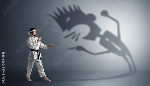 Young karate man fighting with a big black scary shadow 