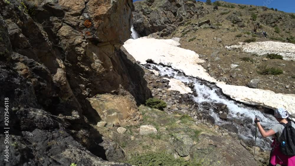 Hikers in the mountains are reaching the waterfall to enjoy an amazing view Hikers in the mountains are reaching the waterfall to enjoy an amazing view
