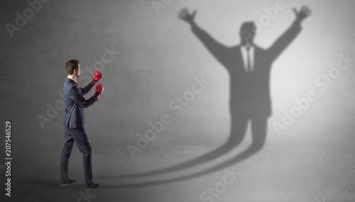 Businessman with boxing gloves fighting with disarmed businessman shadow   © ra2 studio