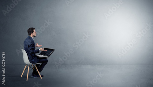 Photos Businessman staying in an empty grey dark room with stuffs on his lap