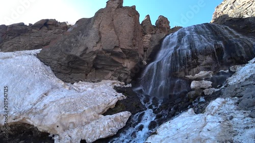 Mountain waterfall view among the rocky mountains and melting snow