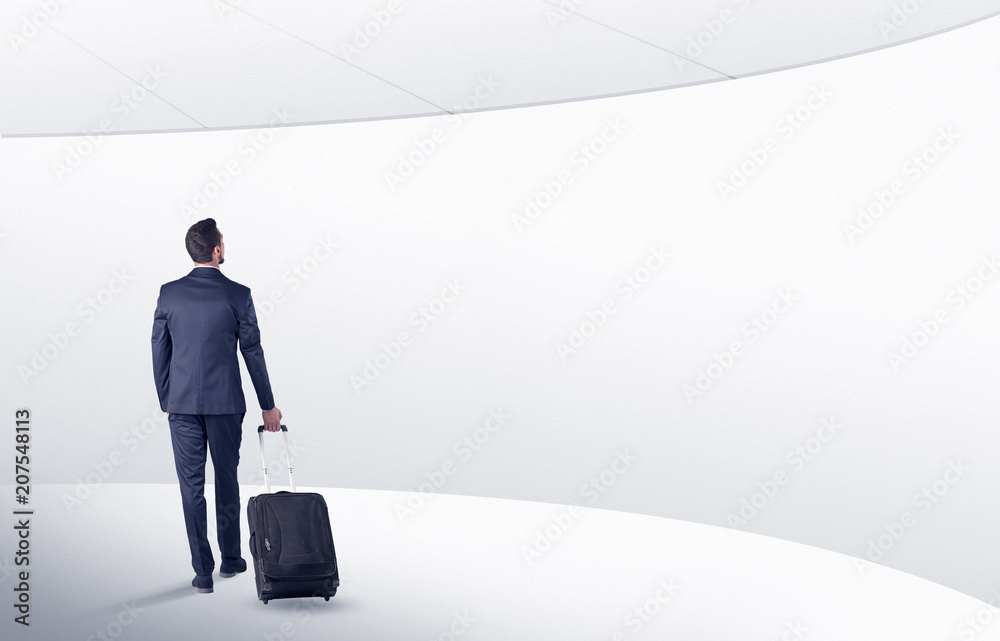 Businessman with back walking in a white waiting room with empty walls around
Businessman with back walking in a white waiting room with empty walls around