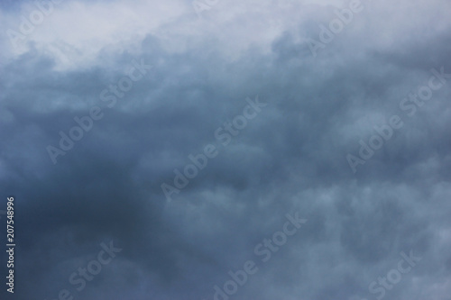A stormy summer cloud of dark blue color carries a heavy downpour.