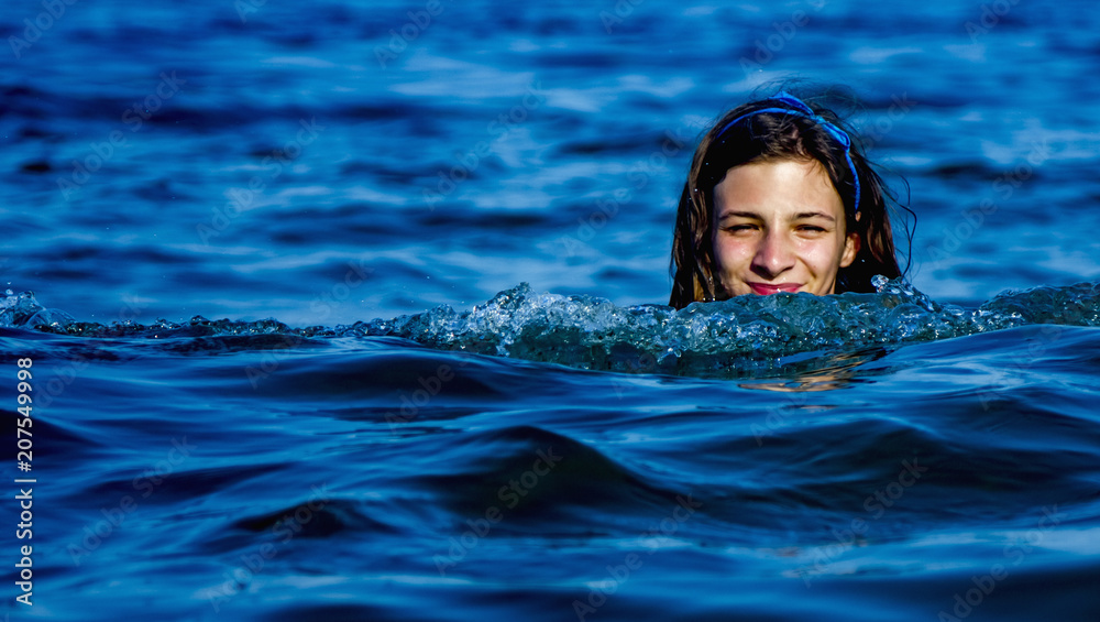 Vacations at sea. Portrait of young beautiful young woman swimming in the transparent sea. (Holiday, rest, travel, childhood concept)