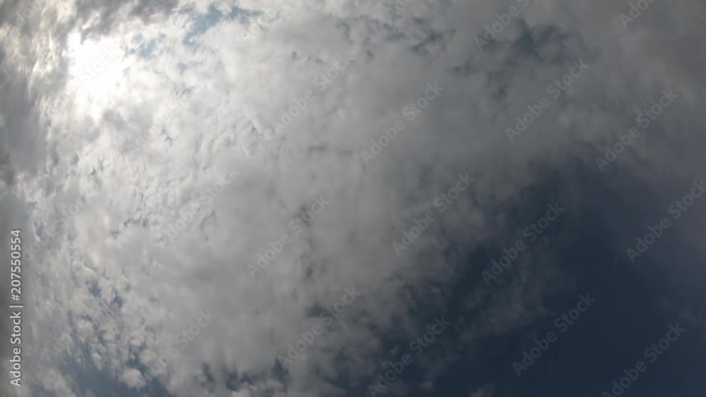 Time lapse of cloudscape with bright sun shining and revealing itself behind clouds.