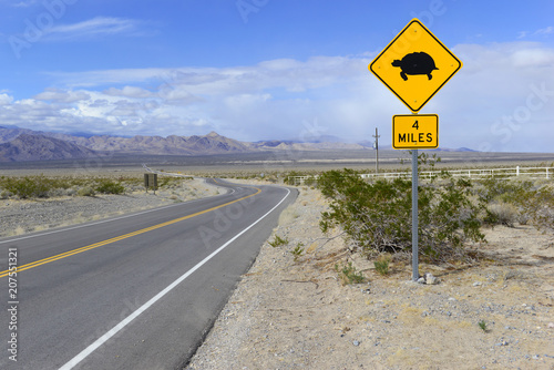 Desert Tortoise crossing warning road sign with mountain backdrop
