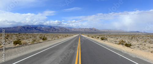 Canvas Print Driving on the open road in the desert with mountain backdrop