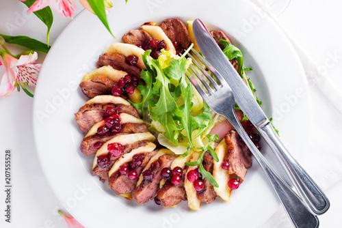 Salad with slices of duck breast with apples and salad under cowberry sauce photo