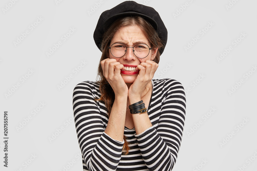 Nervous female traveller with embarrassed miserable expression, bites finger nails, missed her train or plane to other country. Stressed sorrowful young French woman feels worried and depressed Nervous female traveller with embarrassed miserable expression, bites finger nails, missed her train or plane to other country. Stressed sorrowful young French woman feels worried and depressed