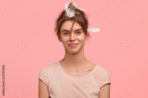 Positive European woman wakes up in good mood as had unforgettable night with lover, wears casual t shirt, isolated over pink background, has gentle warm smile on face. Awakening and good morning © wayhome.studio 