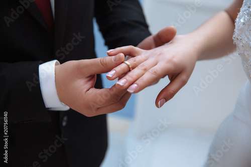 Close-up of the hands of men and women who are getting married. A man puts on a wedding ring on a slender, graceful finger of a girl.
