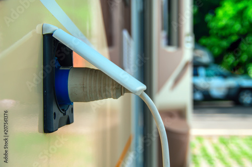 Motorhome stillife. Concept of power supply of the camper in the campsite parking lot. Plug of the electric wire into the socket.