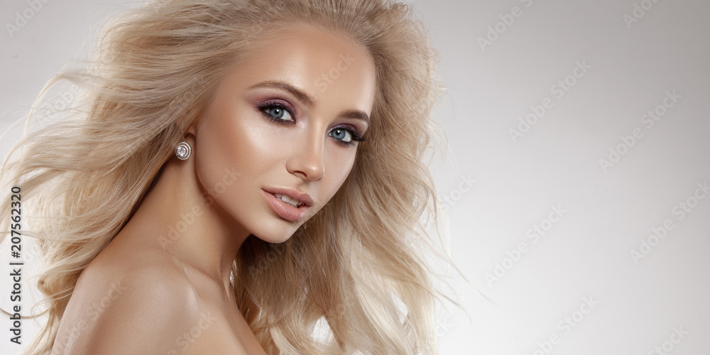 Beauty charming girl blonde. Long healthy hair develops in the wind. Professional make-up, natural lip color. Portrait photographed in studio on a light background. Beauty charming girl blonde. Long healthy hair develops in the wind. Professional make-up, natural lip color. Portrait photographed in studio on a light background.